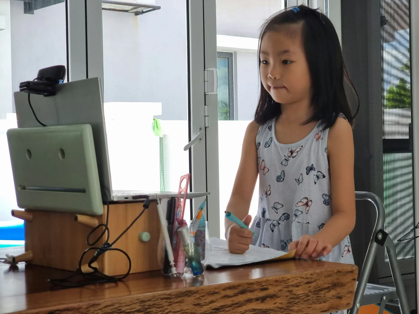 A young student writing at a desk in daylight